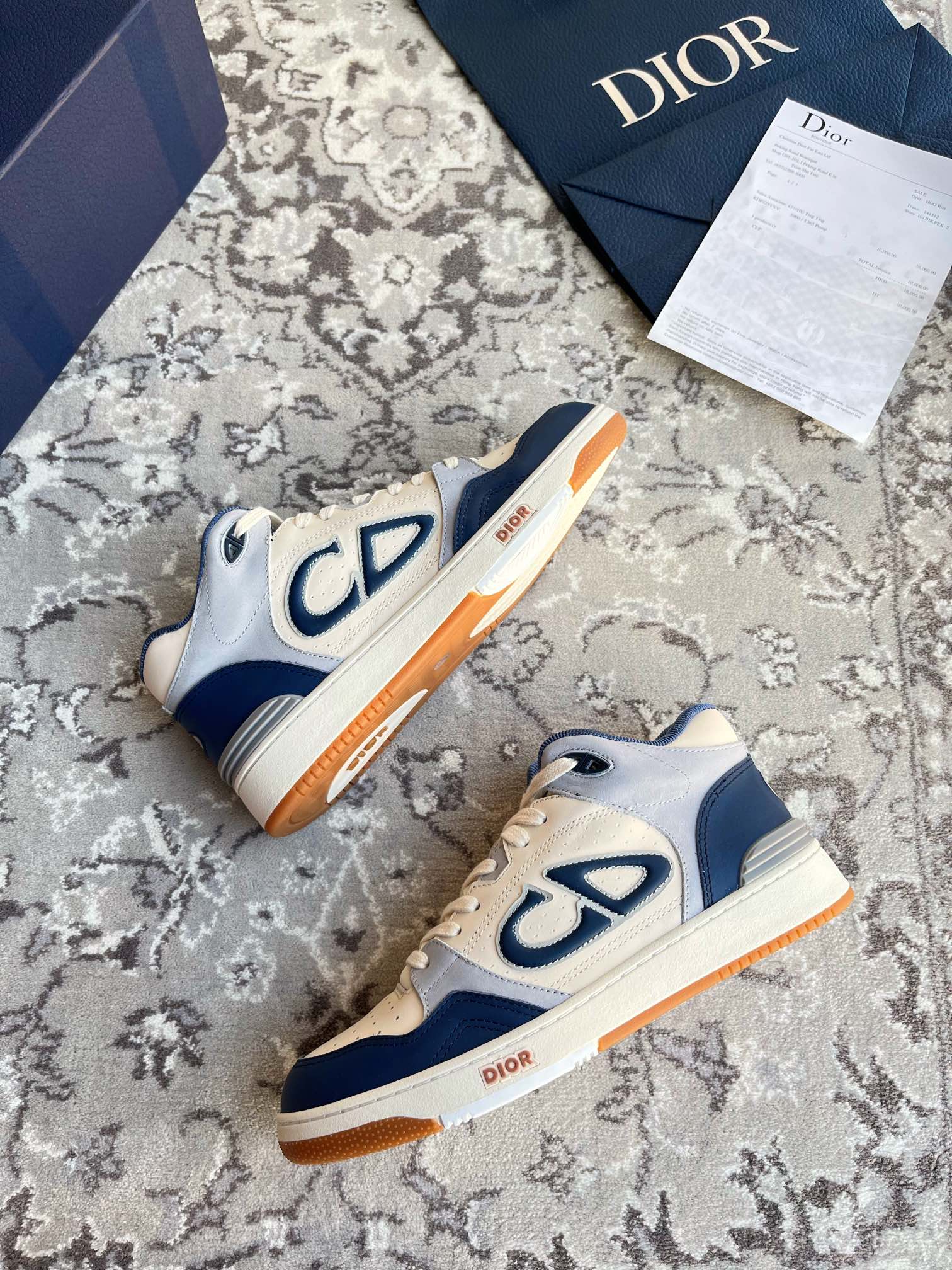 Dior unisex sneakers in cream and navy with CD logo and orange outsole trim.