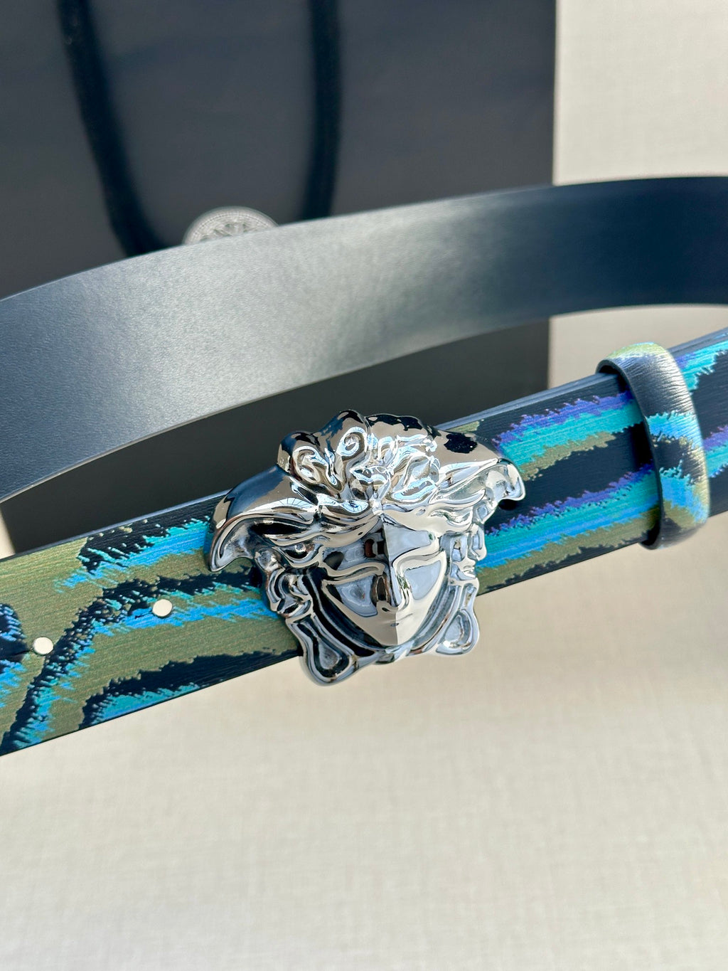 Versace belt strap close-up in blue and teal pattern with ornate silver Medusa buckle