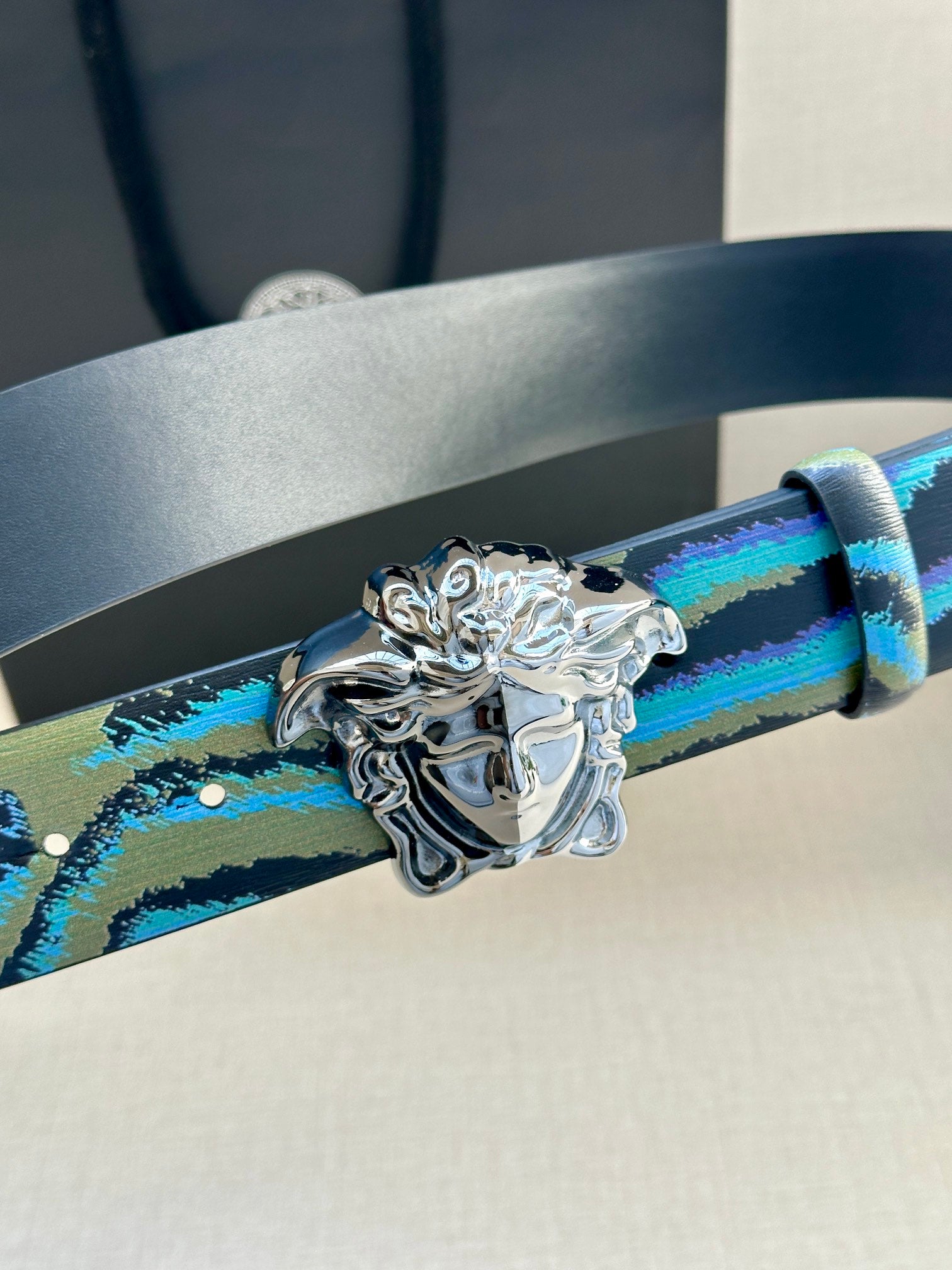Versace belt strap close-up in blue and teal pattern with ornate silver Medusa buckle