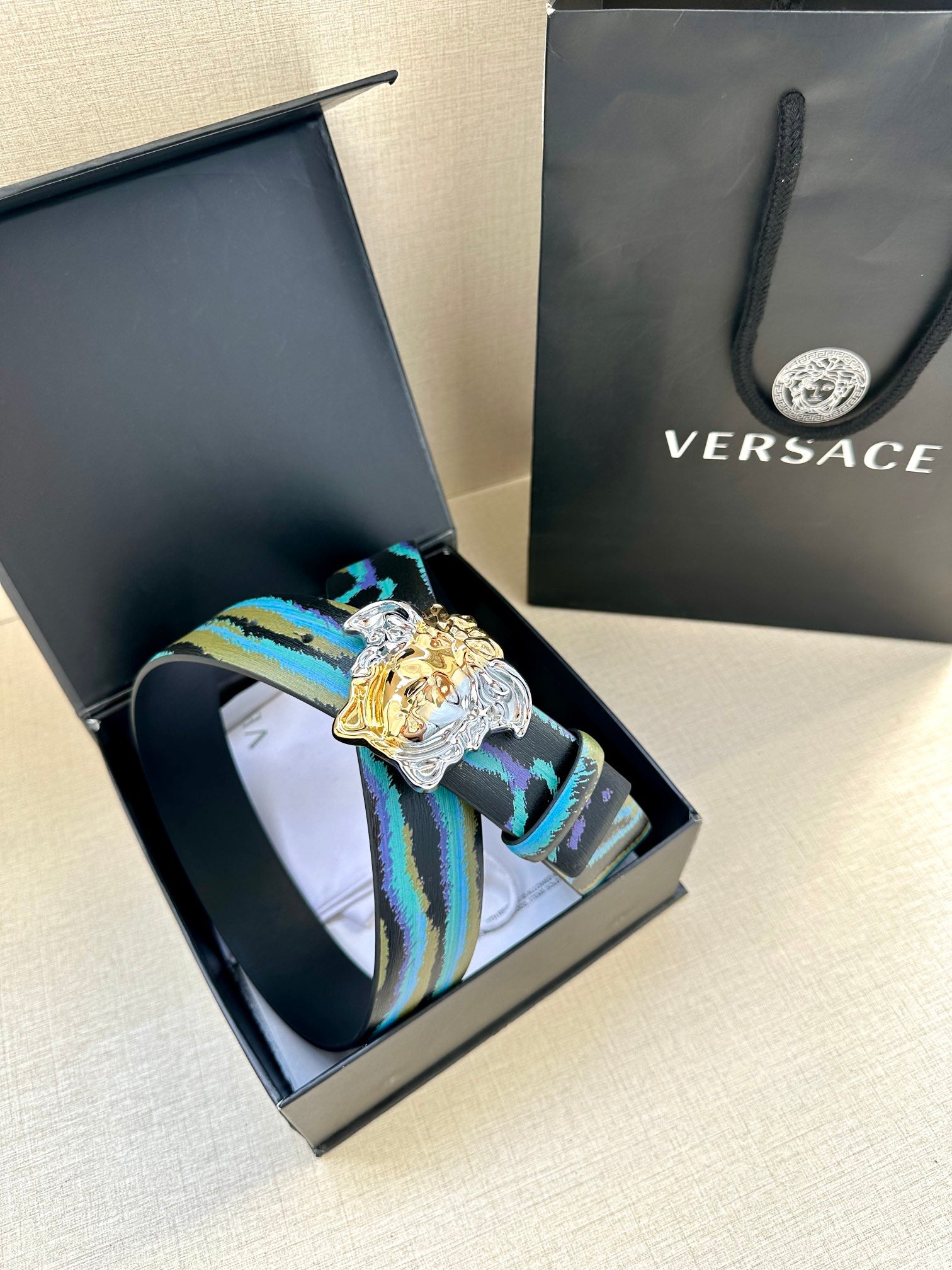 Versace belt with blue and teal striped strap and gold Medusa buckle with silver frame
