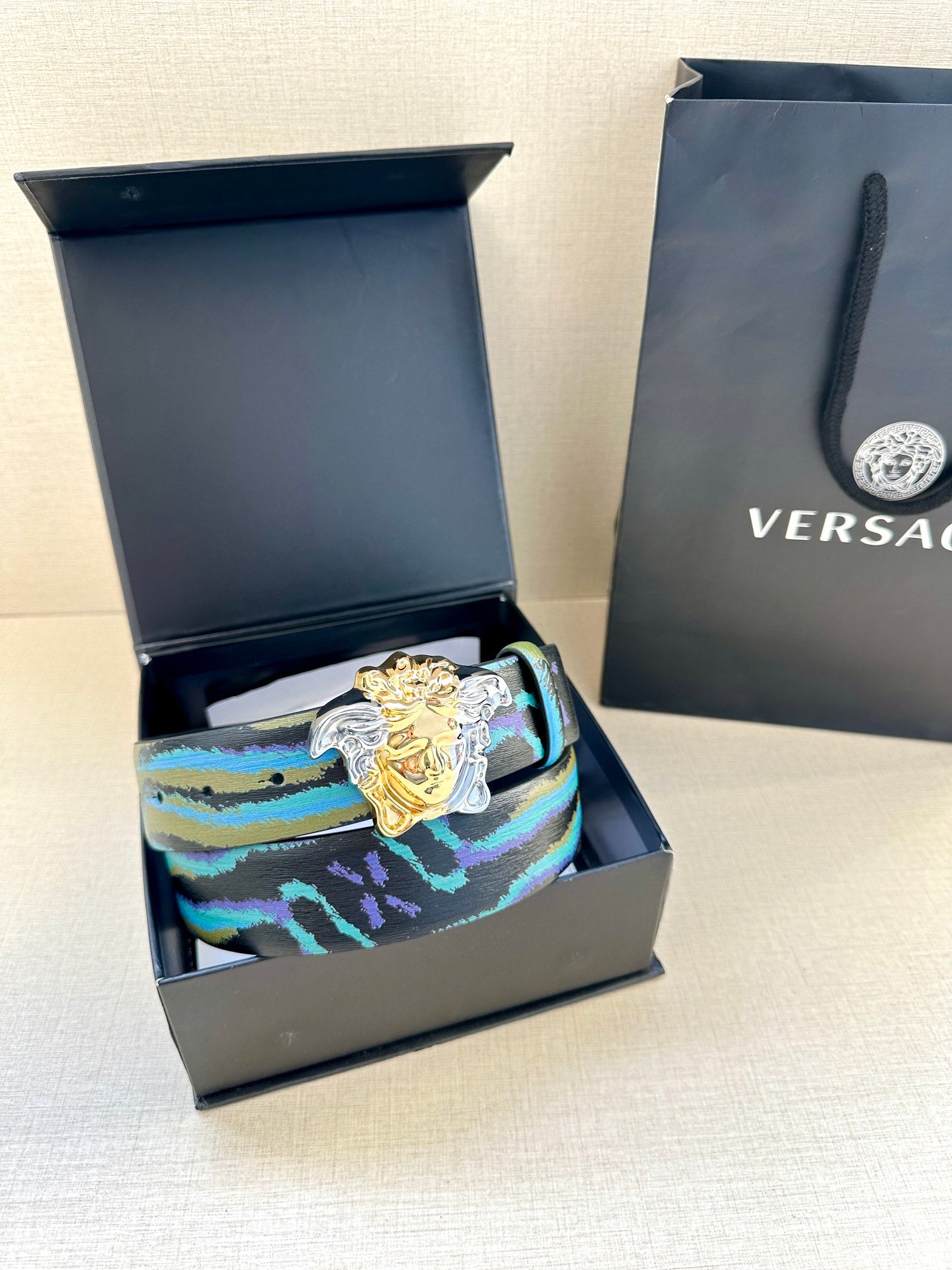 Versace belt with striped blue and teal strap and ornate gold Medusa buckle