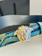 Leather belt close-up: teal-and-blue print strap with gold-and-silver Medusa buckle
