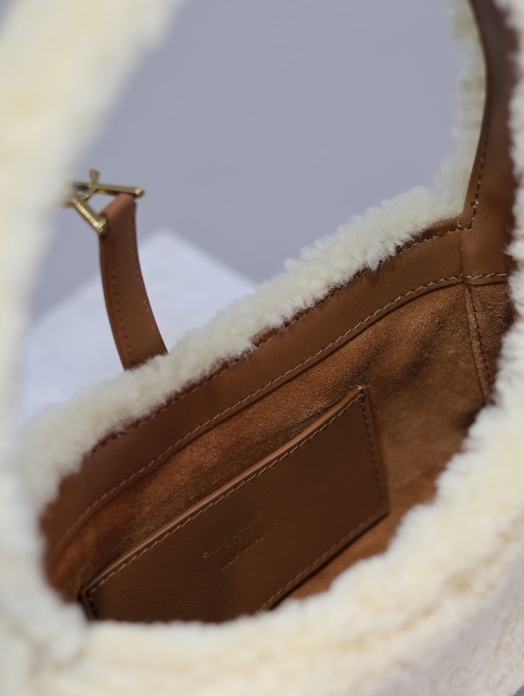YSL shearling bag close-up: brown leather interior panel with gold-tone hardware