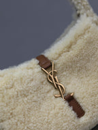 YSL shearling bag close-up: cream fabric with brown leather strap and gold-tone buckle