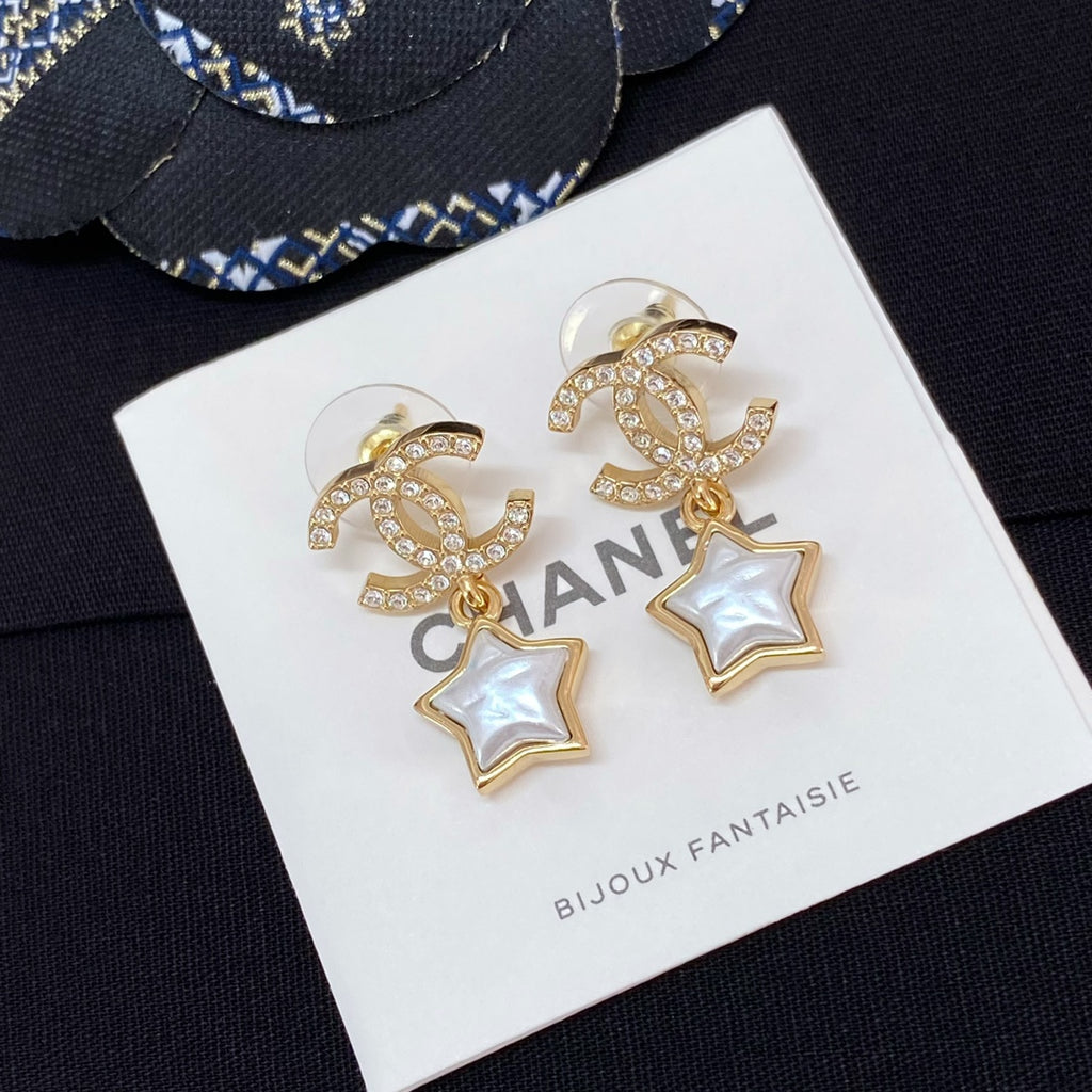 Gold-tone CC star drop earrings with white enamel stars and rhinestone trim on card