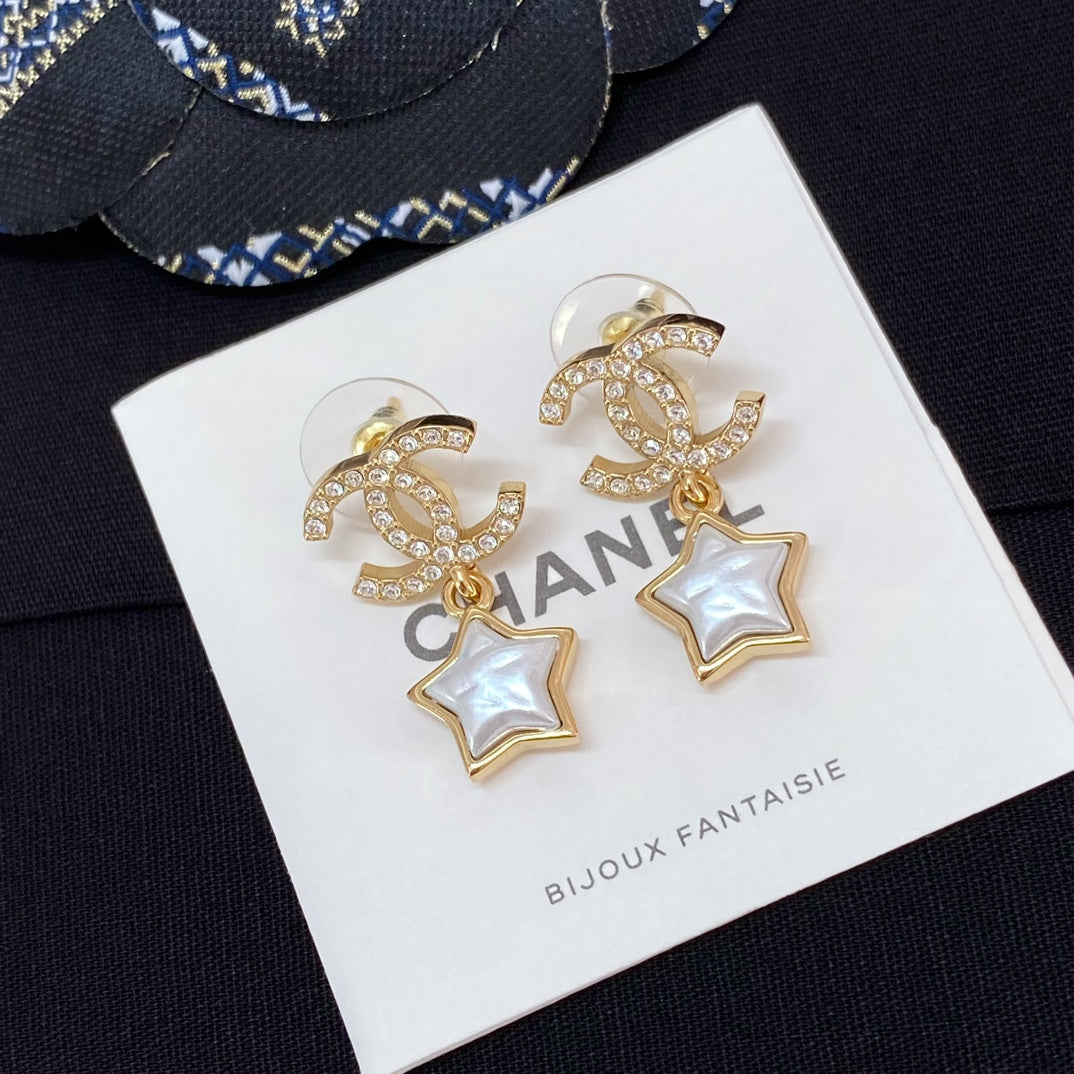 Gold-tone CC star drop earrings with white enamel stars and rhinestone trim on card