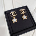 Gold-tone CC star drop earrings with white enamel center and rhinestone details