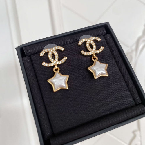 Gold-tone CC star drop earrings with white enamel center and rhinestone details