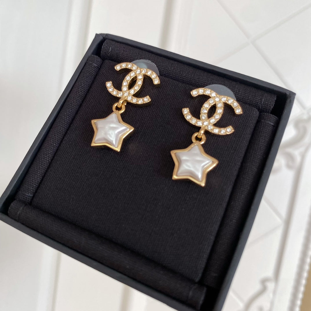 Gold-tone CC star drop earrings with white enamel stars and rhinestone accents