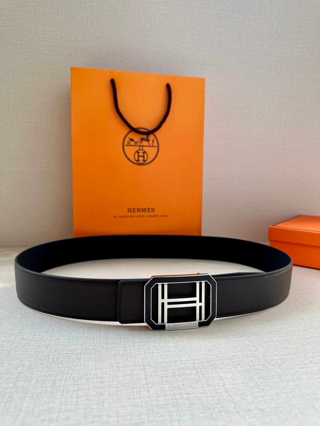 Black leather belt with silver-tone H buckle, laid flat