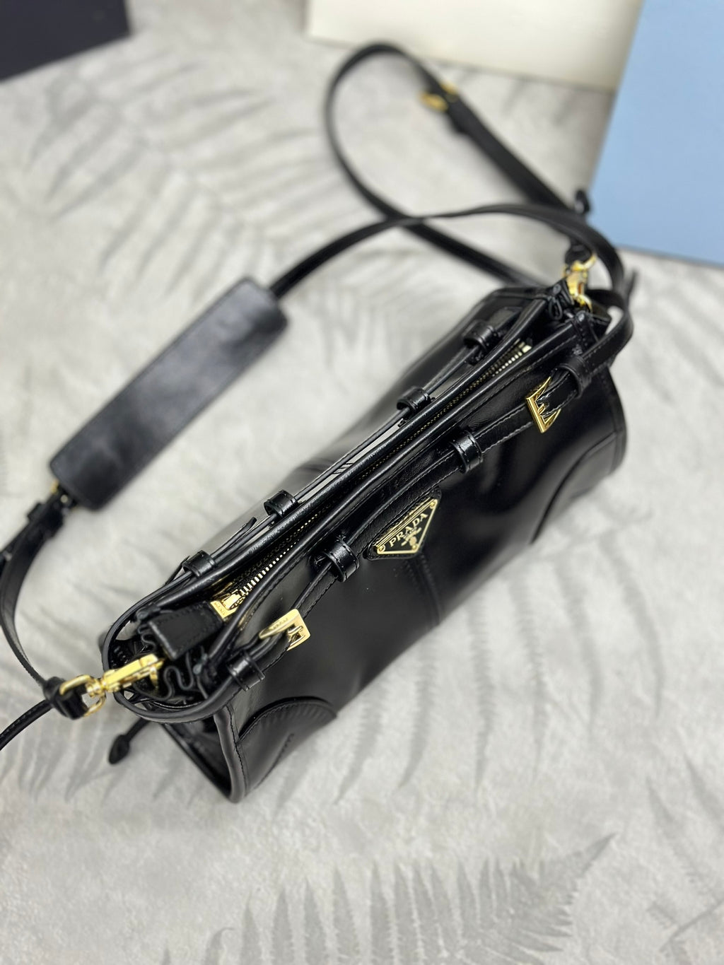 Black leather crossbody bag with long strap, gold-tone zipper pulls, and emblem hardware