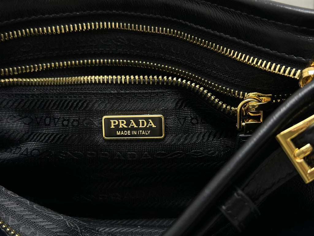 Black fabric lining with Prada Made in Italy label and gold zipper pull