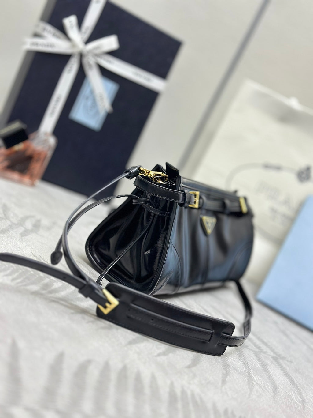 Black leather satchel bag with adjustable shoulder strap and gold-tone buckle accents