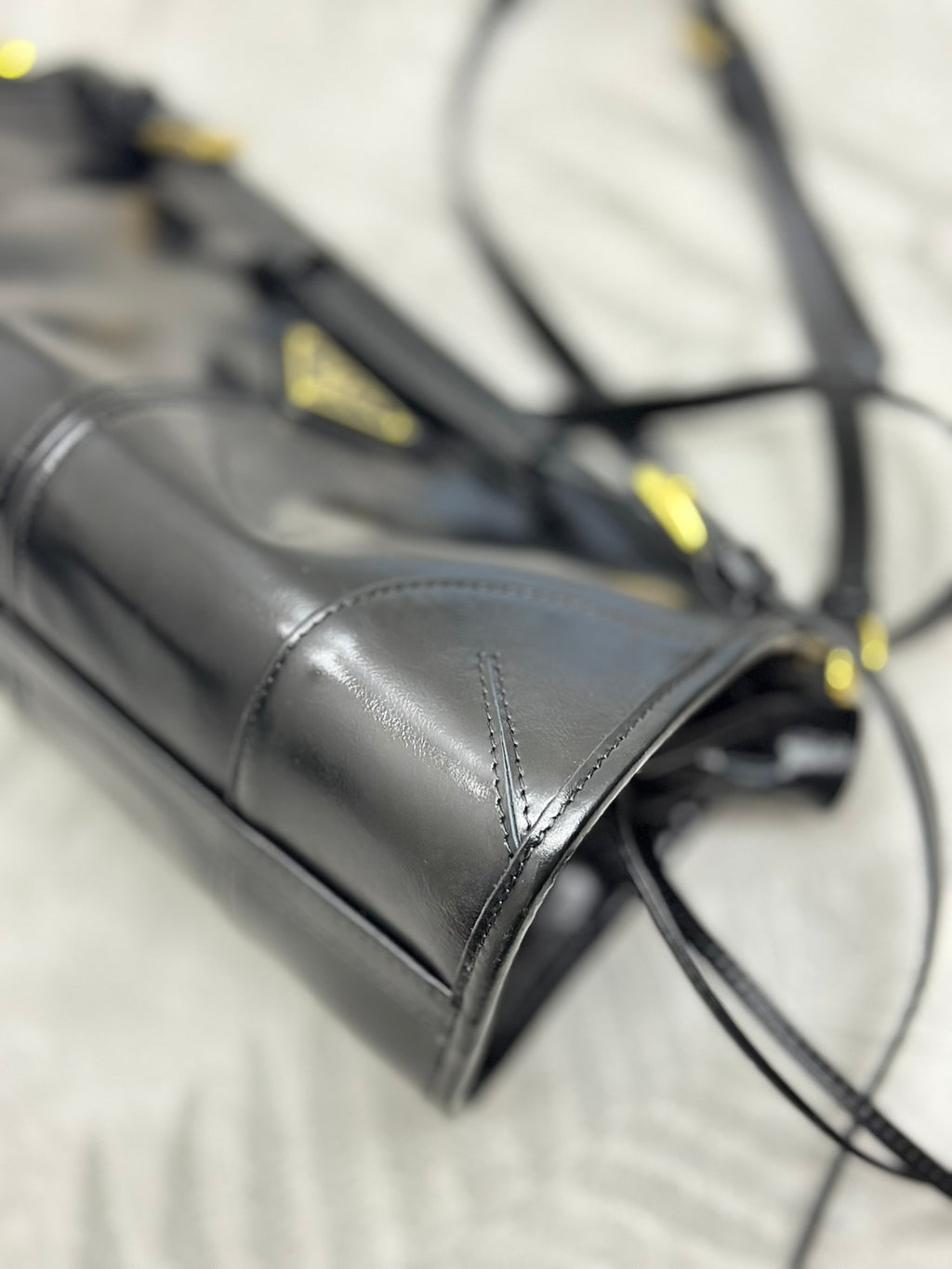 Black leather bag corner with gold-tone stitching and attached strap