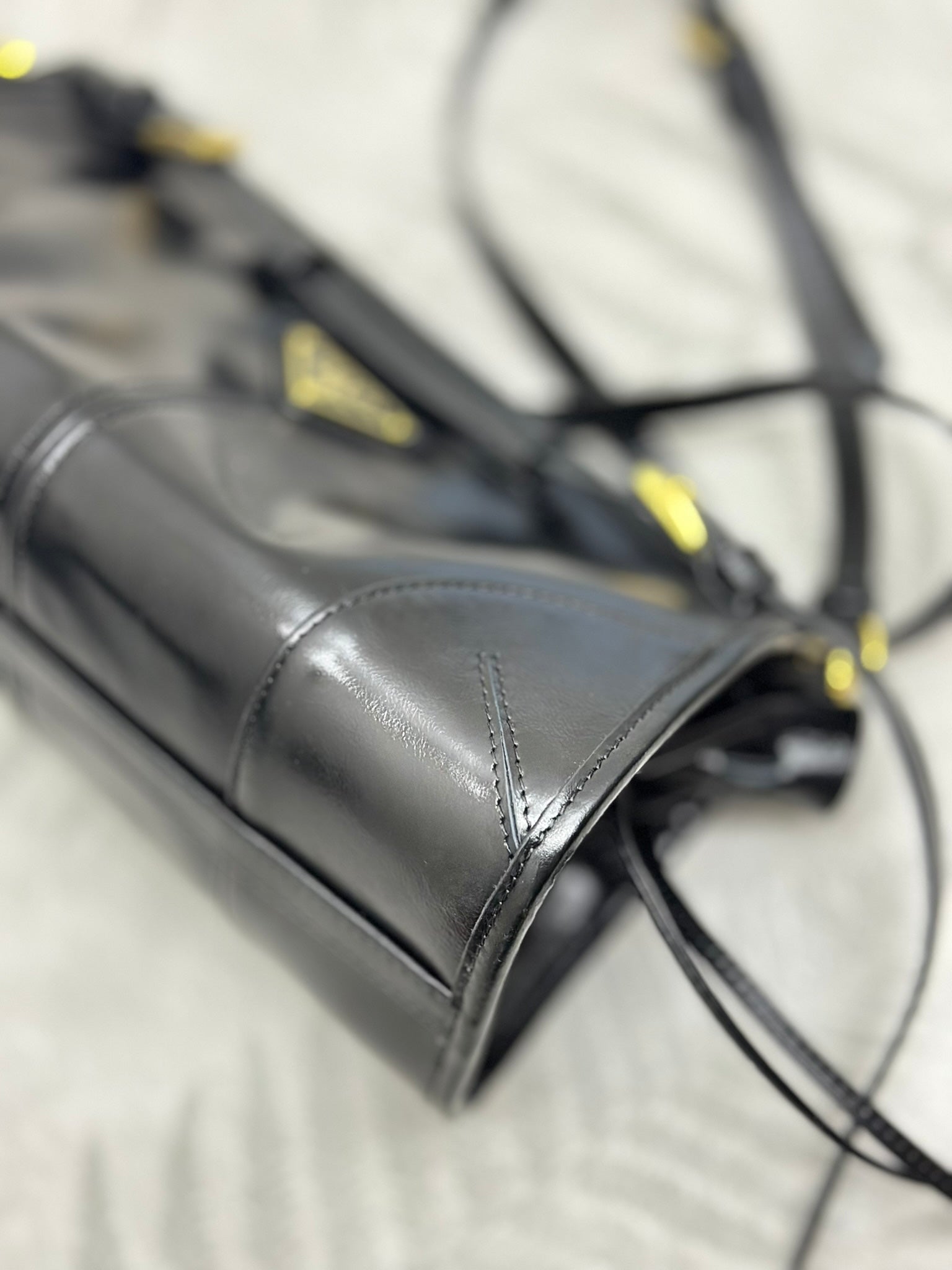 Black leather bag corner with gold-tone stitching and attached strap