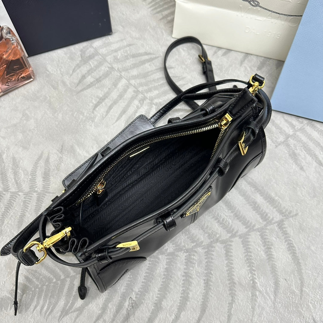 Black leather mini bag with front zipper, gold-tone hardware, and crossbody strap