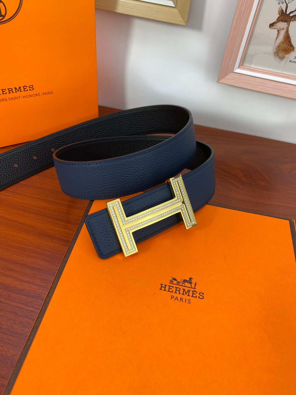 Blue leather belt with textured surface and gold-tone H buckle on folded strap