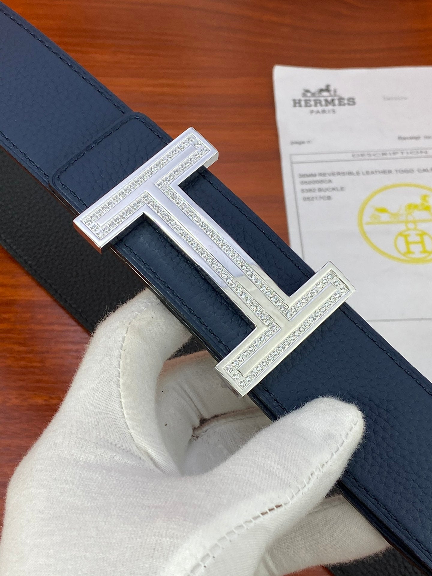 Close-up blue leather belt with textured strap and silver H buckle