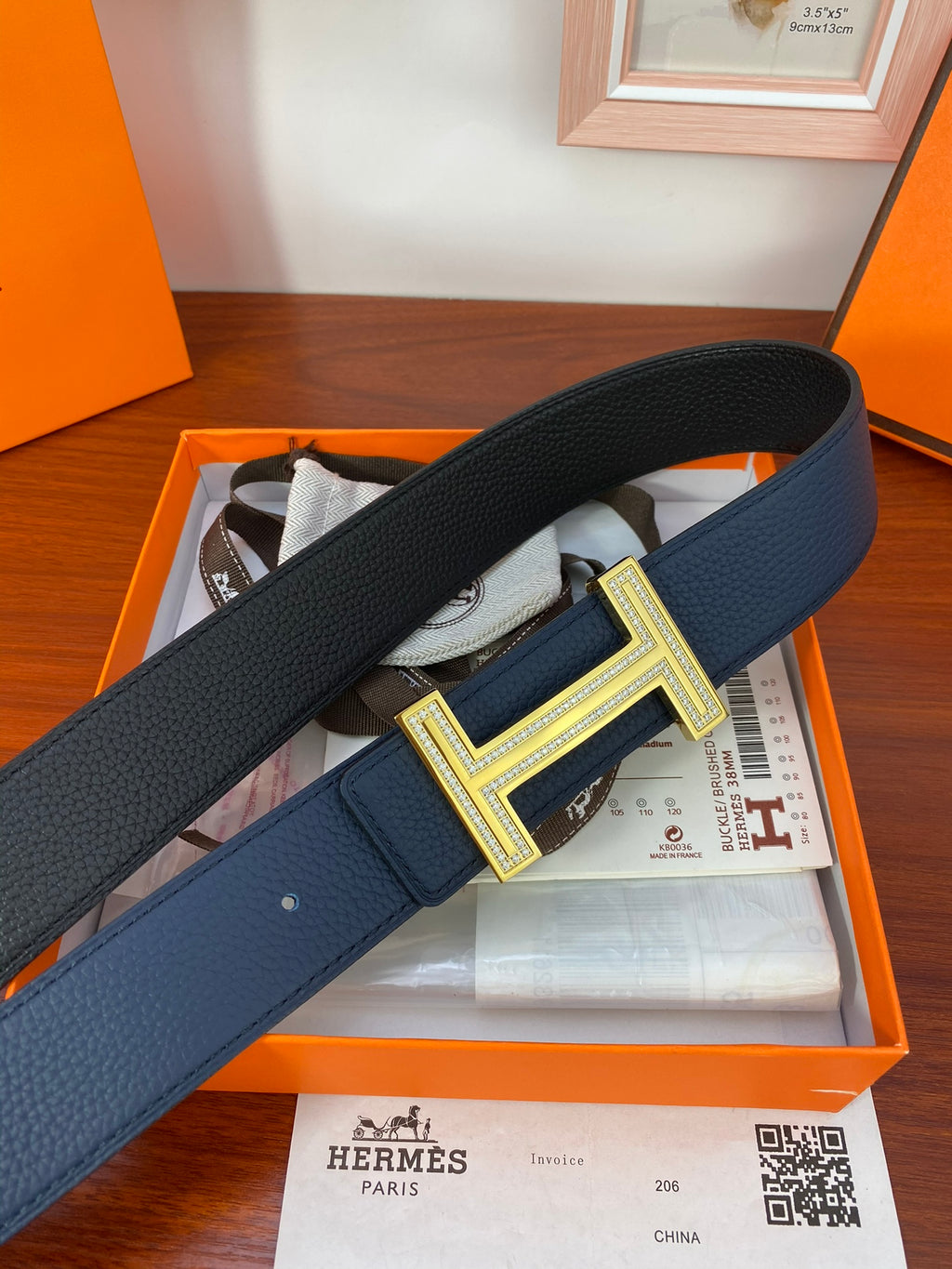 Blue leather belt with textured finish and large gold-tone H buckle centerpiece
