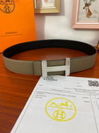 Hermes reversible belt with light olive strap and dark underside, silver buckle across center