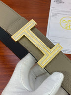 Hermes reversible belt close-up: textured light olive leather strap and silver H buckle