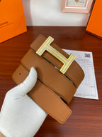 Reversible leather belt with tan strap and silver H buckle on dark keeper tab.