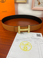 Two-tone leather belt with tan strap and silver H buckle, dark inner side.