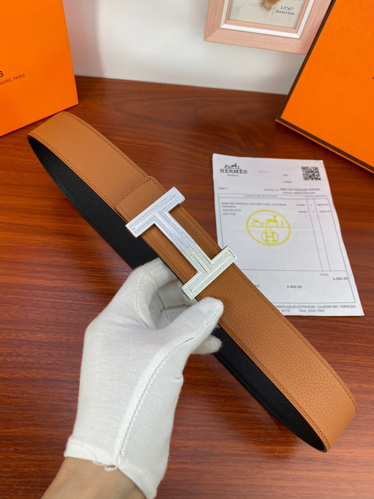 Reversible leather belt with tan and dark sides and silver H buckle detail.