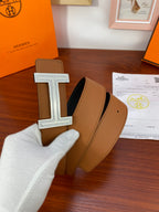 Two-tone leather belt, tan and dark, with silver H buckle and engraved border.