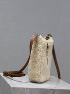 Cream shearling-style handbag with brown leather shoulder strap and gold hardware