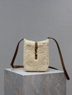 Shearling-style crossbody bag with brown leather straps and hanging cord charm