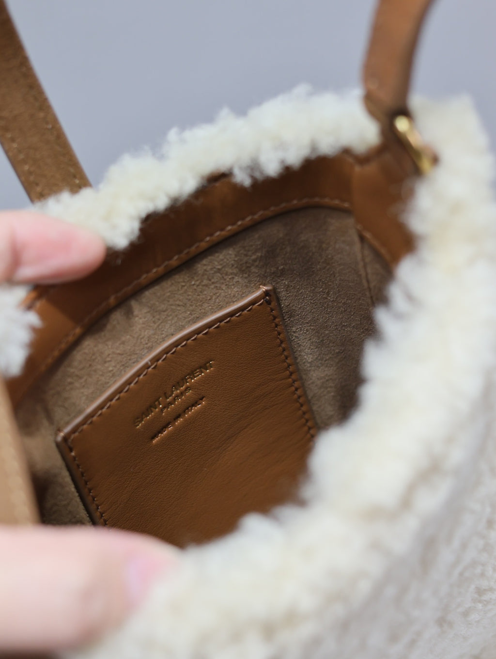 Close-up of brown leather front with embossed logo detail on shearling trim