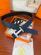 Hermès belt in dark blue leather with silver-tone buckle, shown in gift box.