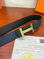 Hermès belt detail: dark blue pebbled leather with gold-tone H buckle.