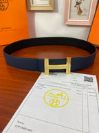Hermès belt in dark blue leather with gold-tone buckle, laid flat.