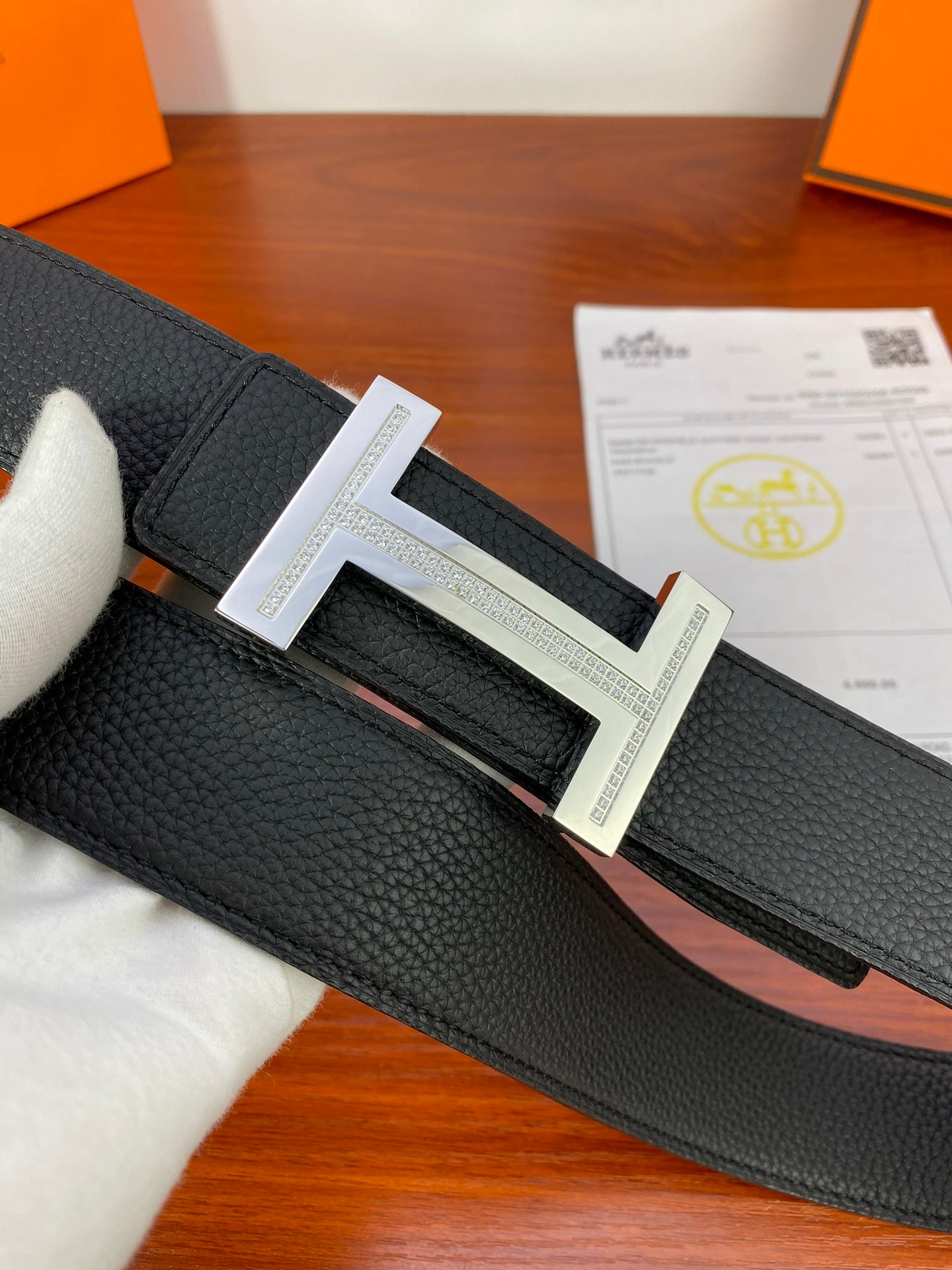 Black textured leather belt with silver H buckle close-up