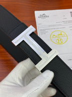 Black textured leather belt with silver H buckle and engraved border