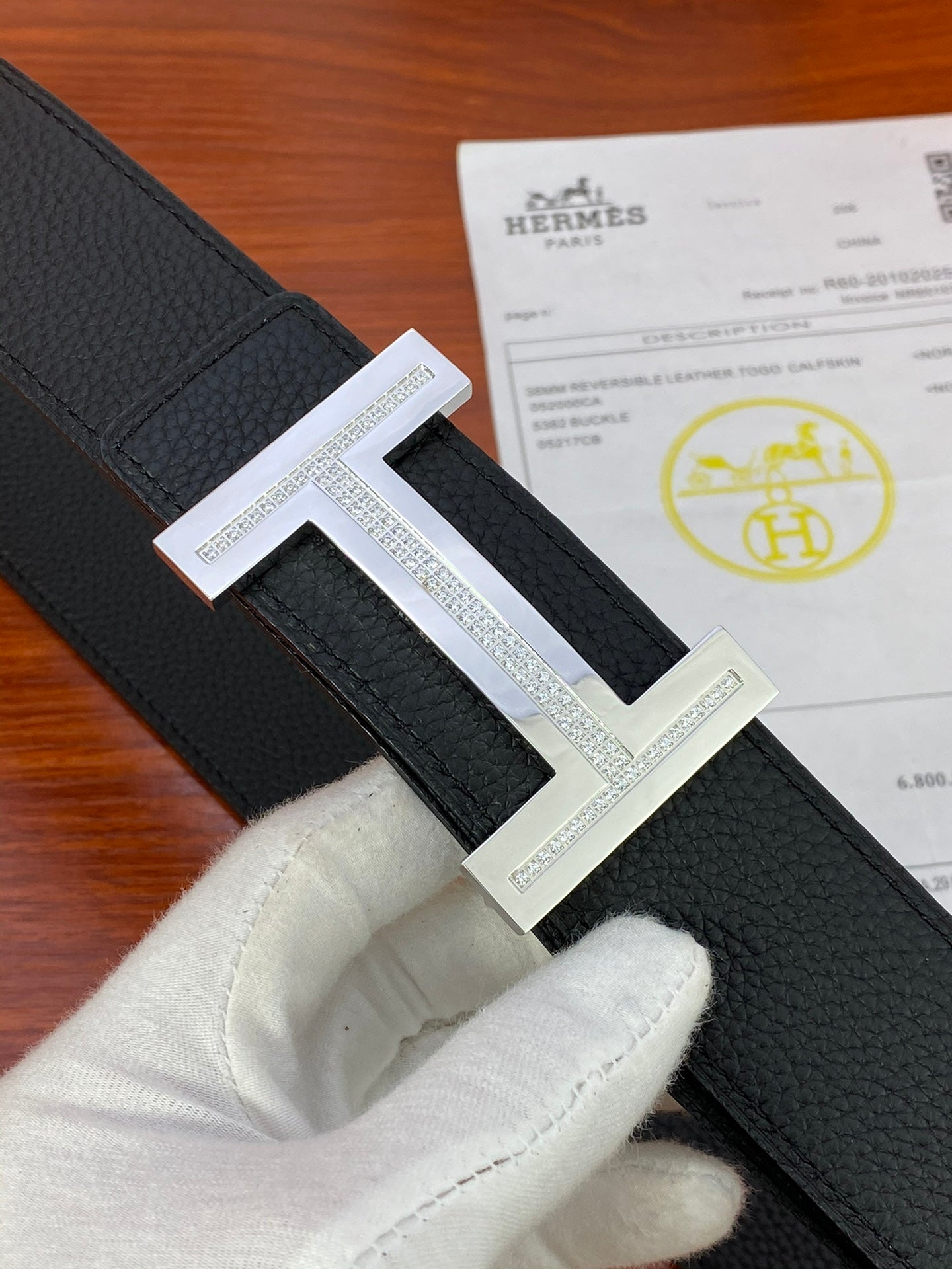 Black textured leather belt with silver H buckle and engraved border