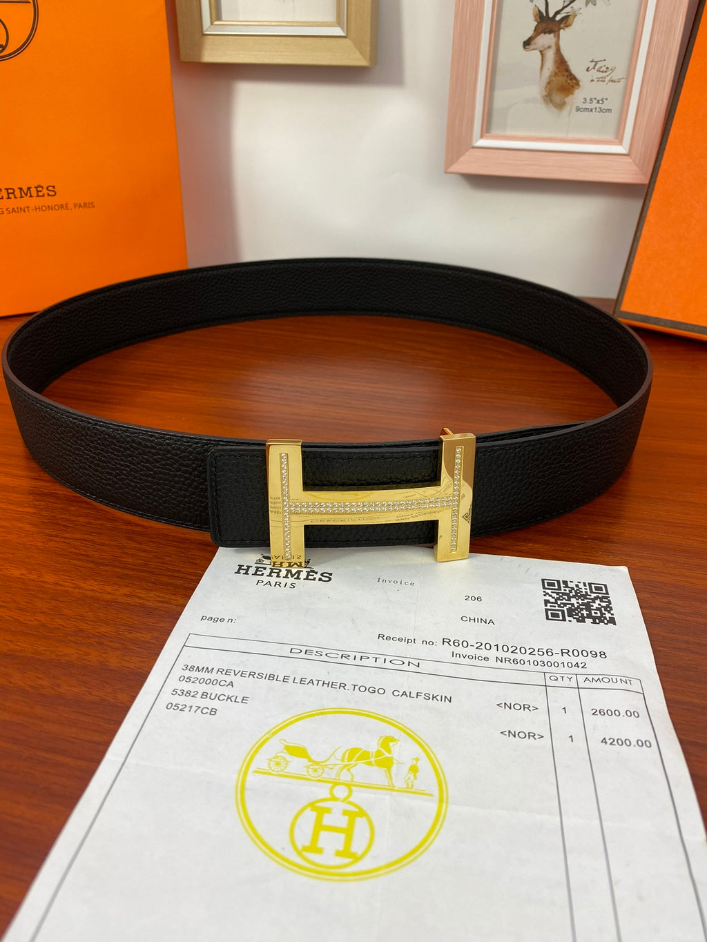 Black textured leather belt with gold H buckle and leather strap holes