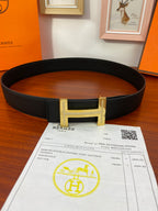 Black textured leather belt with gold H buckle and leather strap holes