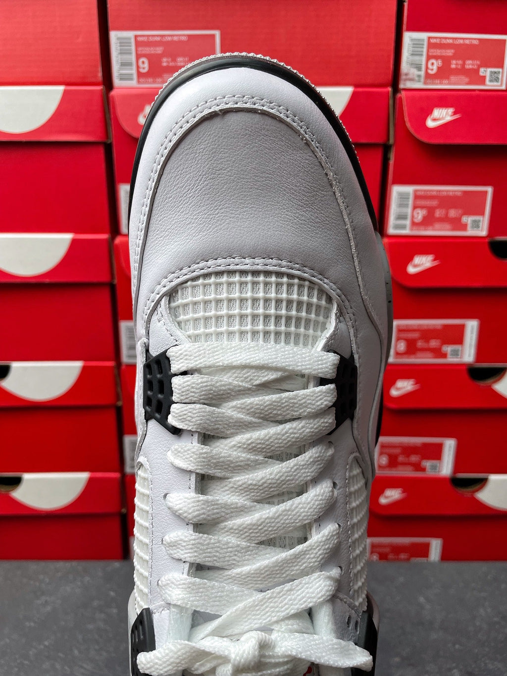 White high-top sneaker toe with woven panel, white laces, and gray accents