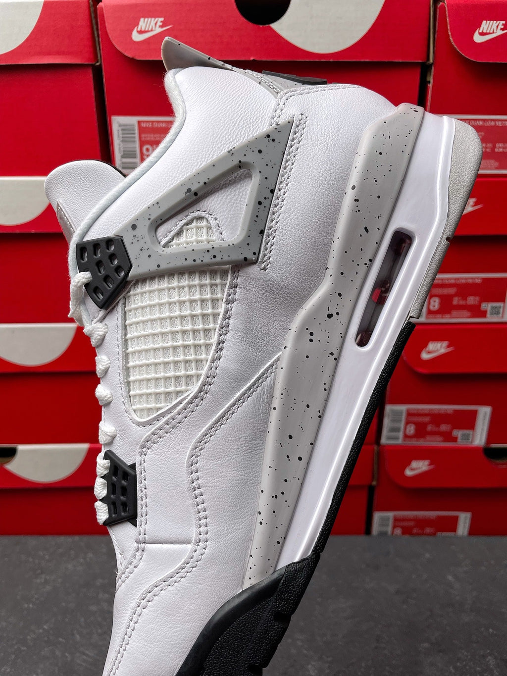White high-top sneaker with gray speckled accents and black lace wings