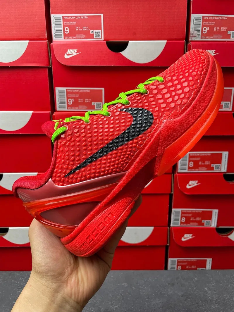 Red low-top basketball shoe with black swoosh and neon green lace-up, held in hand.