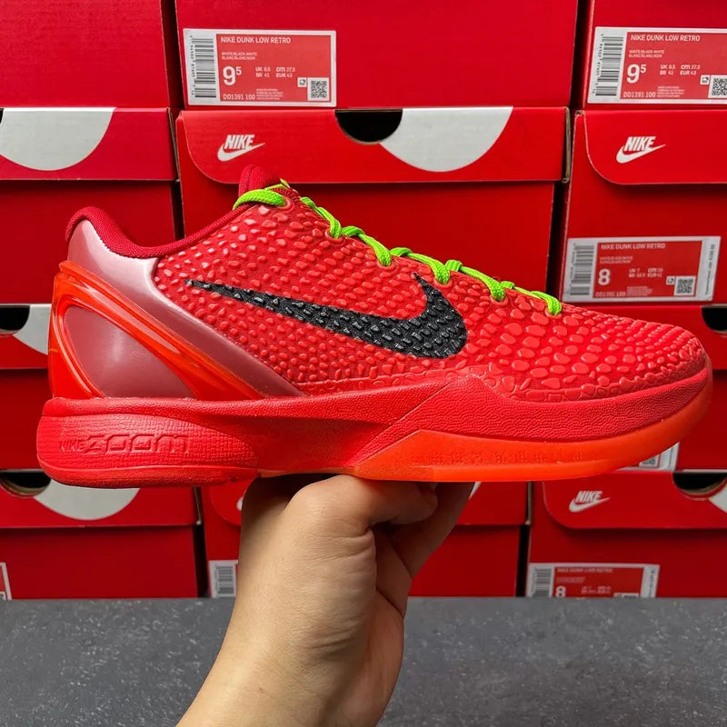 Red textured basketball shoe with black swoosh and neon green laces, side-front view.