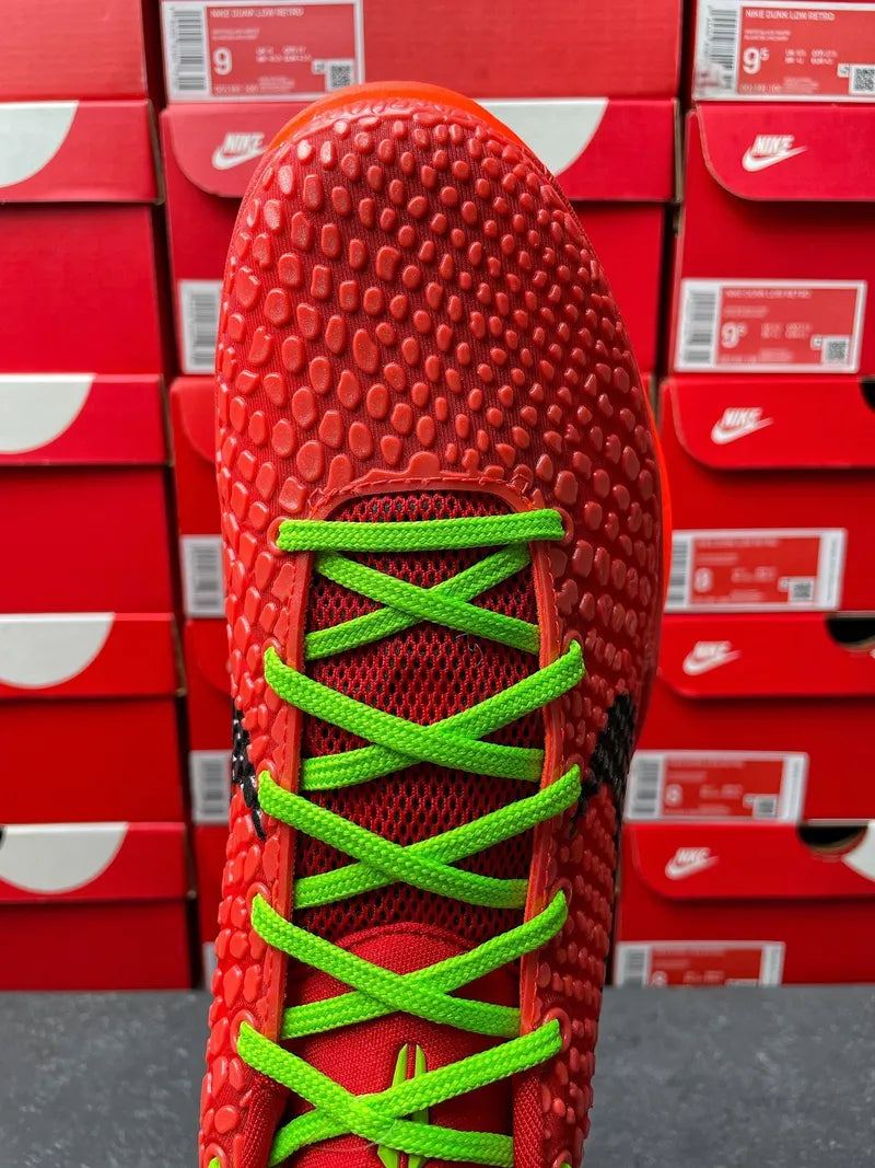 Red shoe upper with neon green laces and lace loops, close-up of toe area.
