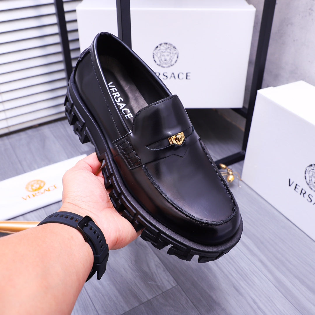 Black Versace leather loafer, gold buckle emblem, chunky outsole, held in hand