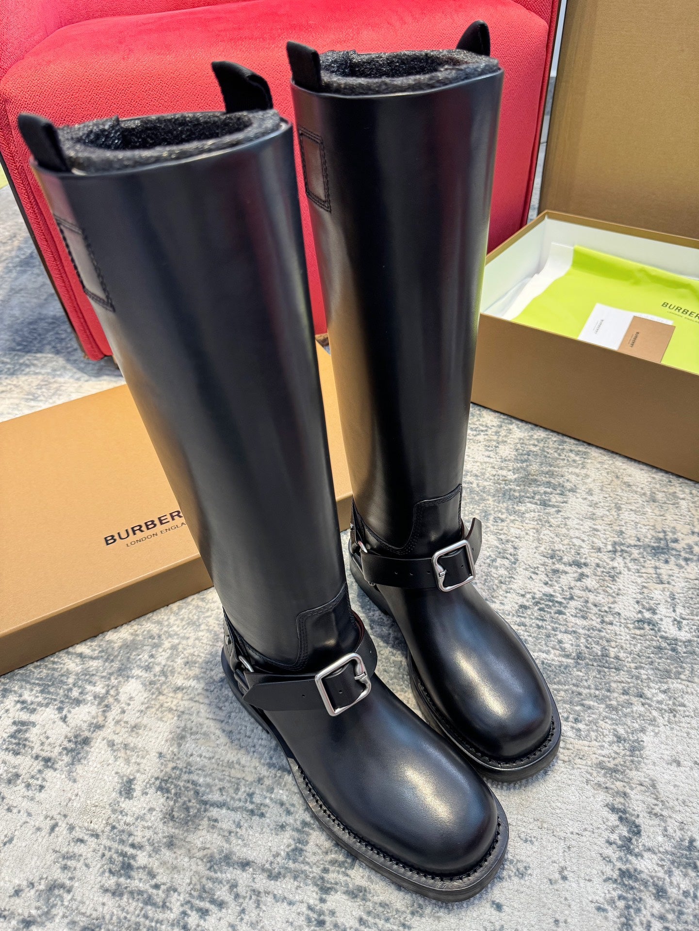 Pair of black knee-high boots with buckled strap details and textured cuff lining