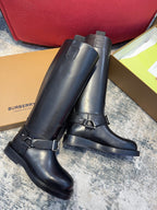 Black knee-high boots with adjustable buckle straps and low-profile rubber soles