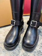 Close-up of black knee-high boots with metal buckle straps and stitched panels