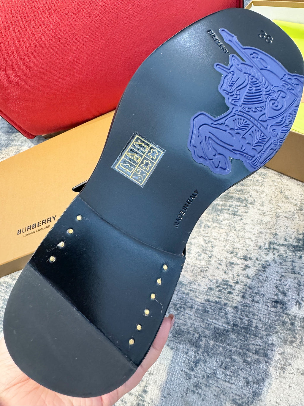 Black boot outsole with embossed logo and small metal stud accents on strap edge